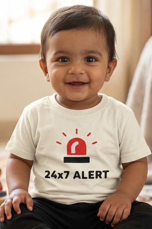 Child wearing a shirt with '24x7 Alert' design sitting on a rug.