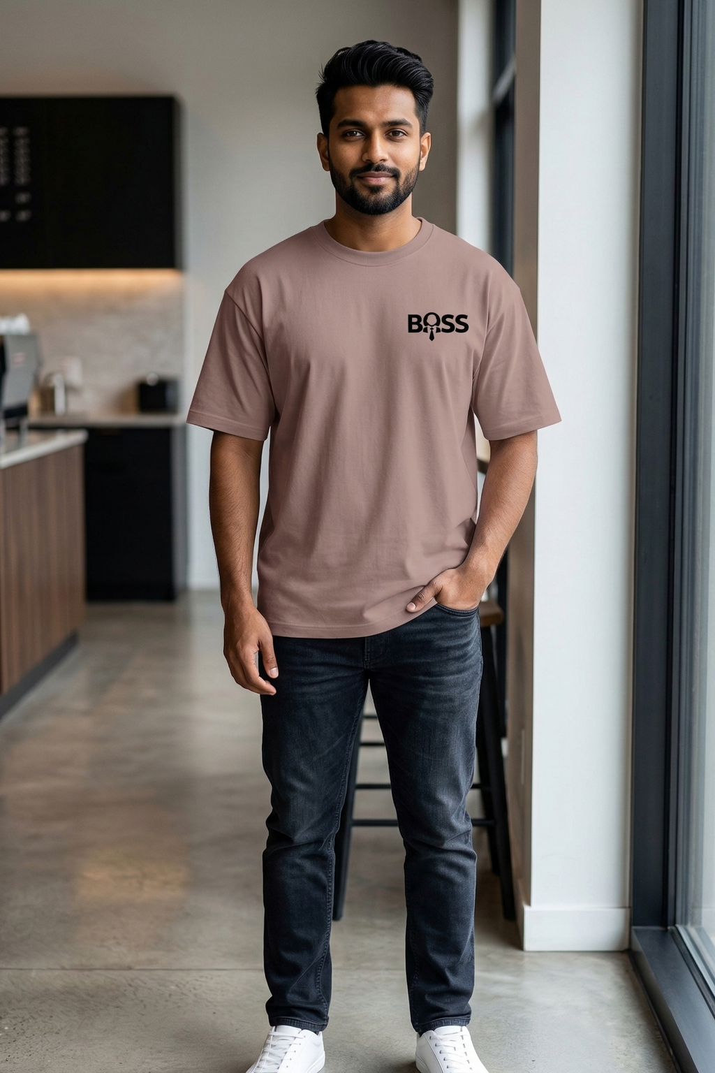 Man wearing a brown 'BOSS' t-shirt in a modern kitchen.