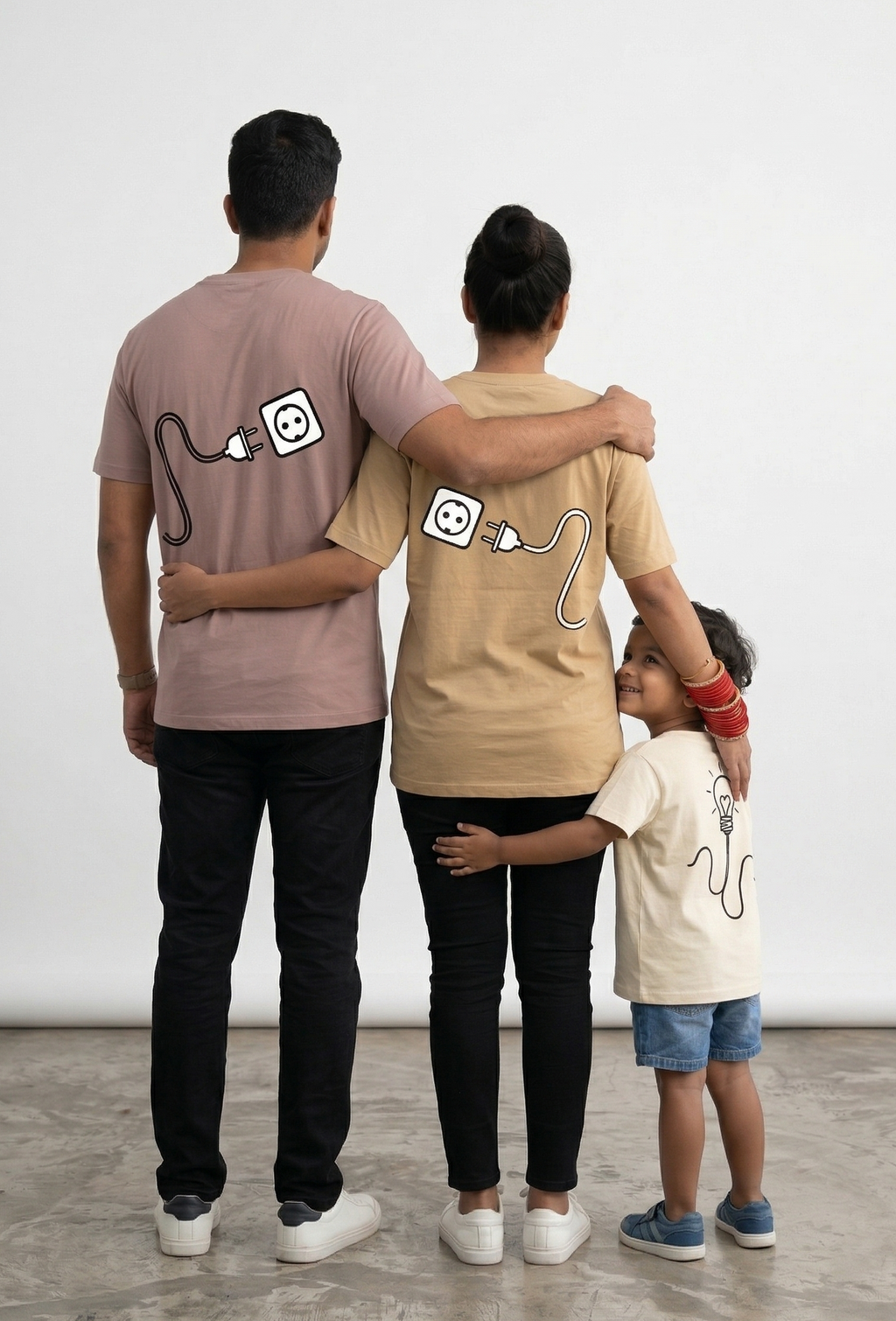 Family of three wearing matching t-shirts with a design on a plain background