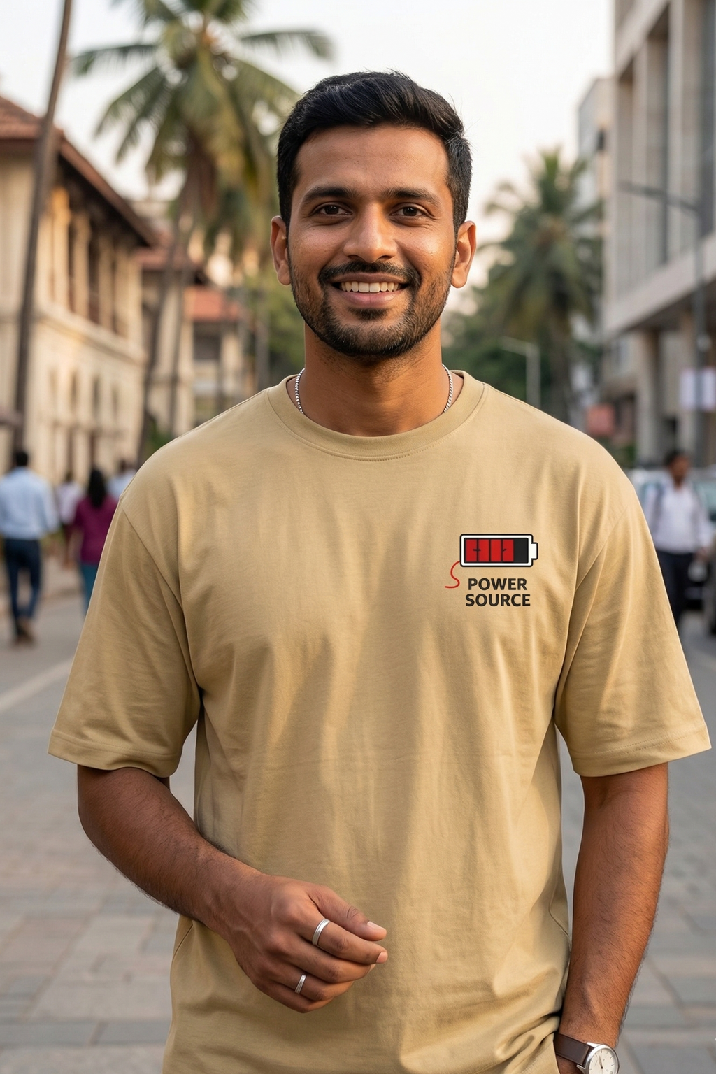 Man wearing a beige t-shirt with a logo on a street