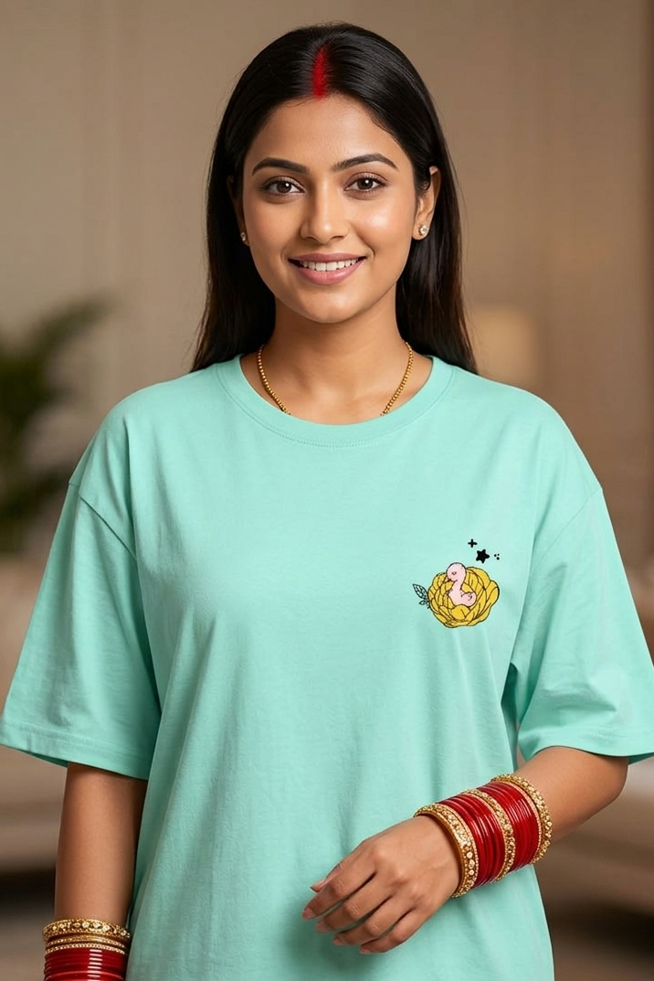 Woman wearing a light blue t-shirt with a small design on it, standing indoors.