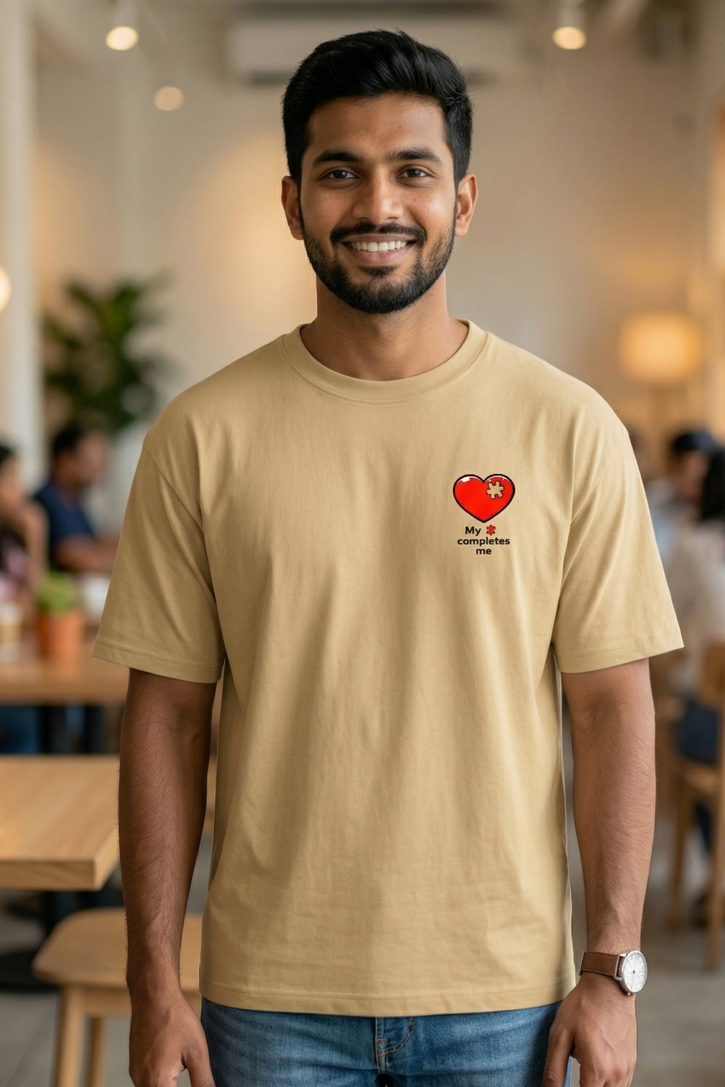 Man wearing a beige t-shirt with a red heart design in a casual setting