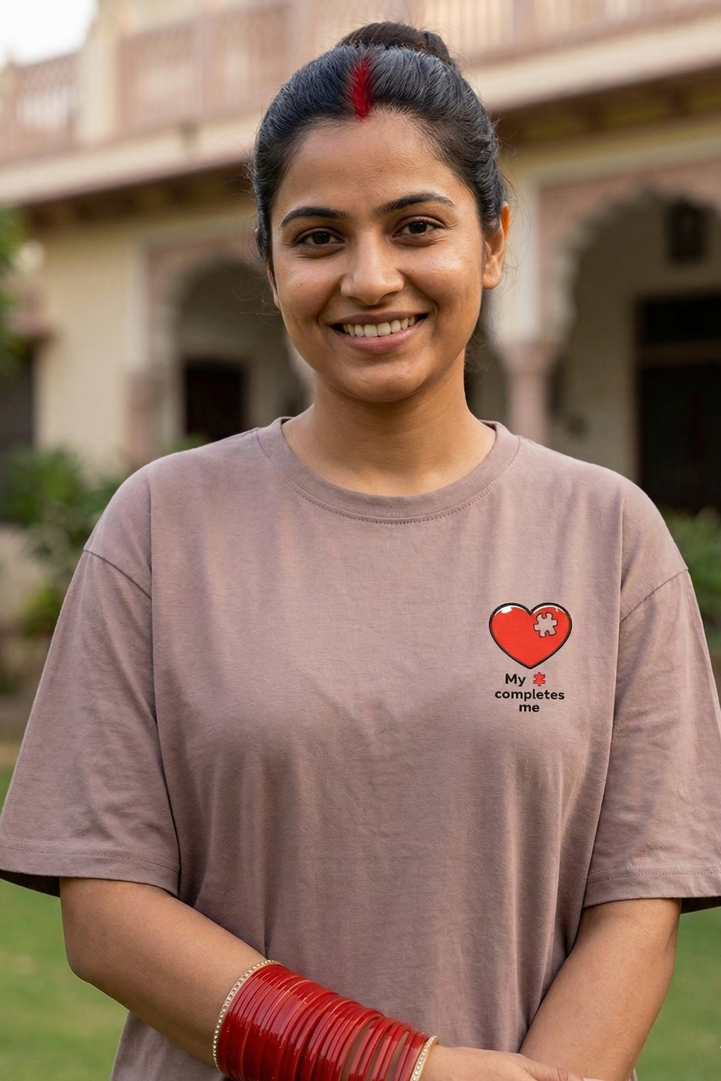 Woman wearing a brown t-shirt with a heart design and text, standing outdoors.