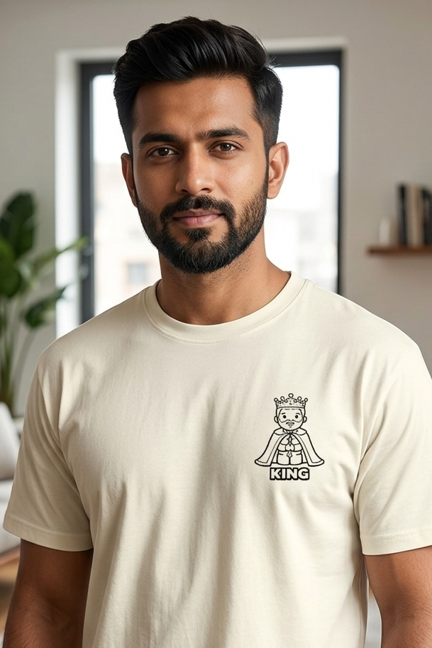 Man wearing a beige t-shirt with a king design in a living room