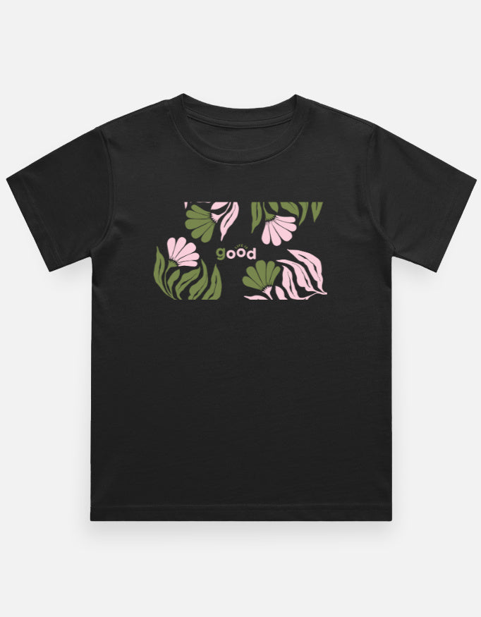 A black short-sleeve crewneck t-shirt featuring a graphic print on the chest with pink flowers, green leaves, and the word 'good' in small letters, displayed against a light gray background.