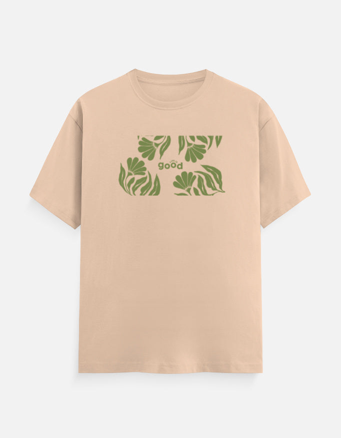 A light peach-beige short-sleeve t-shirt with a green graphic print of tropical leaves and the word 'good' on the chest, displayed against a light gray background.
