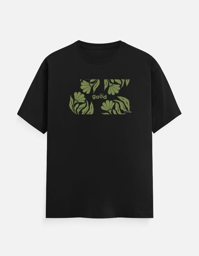 A black short-sleeve crewneck t-shirt featuring a green graphic print of tropical leaves and the word 'good' on the chest, displayed against a light gray background.