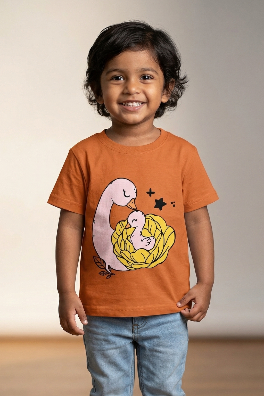 Child wearing an orange t-shirt with a graphic design on a plain background