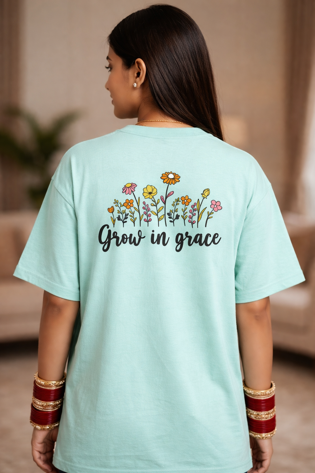 Person wearing a light blue t-shirt with floral designs and 'Grow in grace' text.