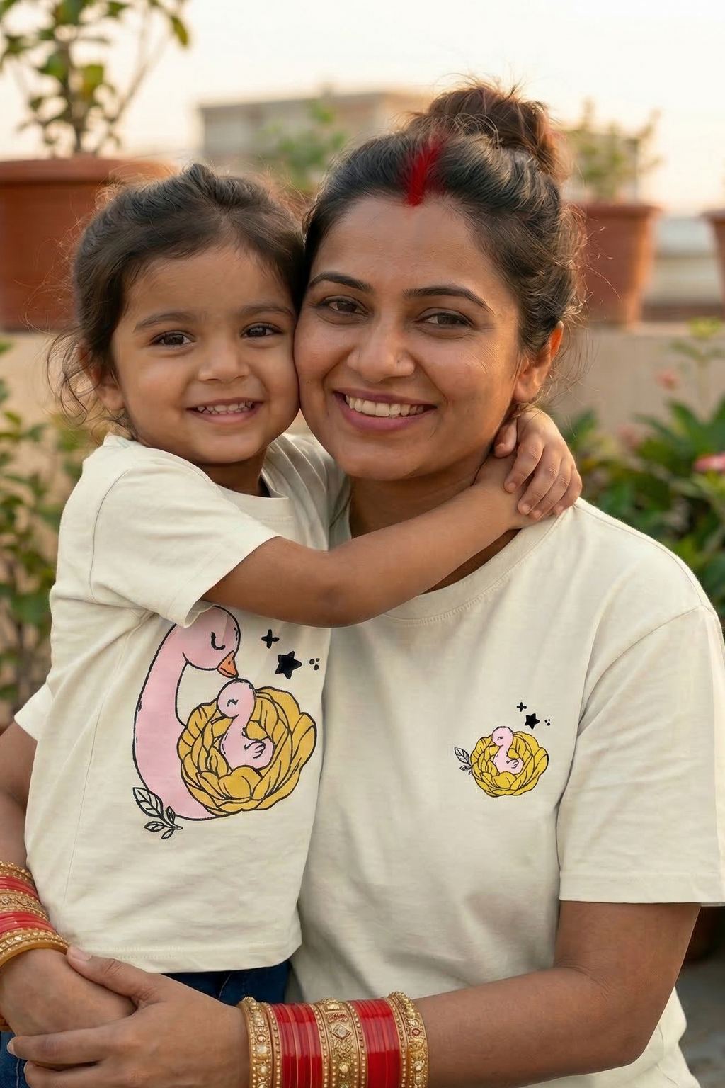 Woman and child wearing matching t-shirts with a duck design on a rooftop with plants in the background