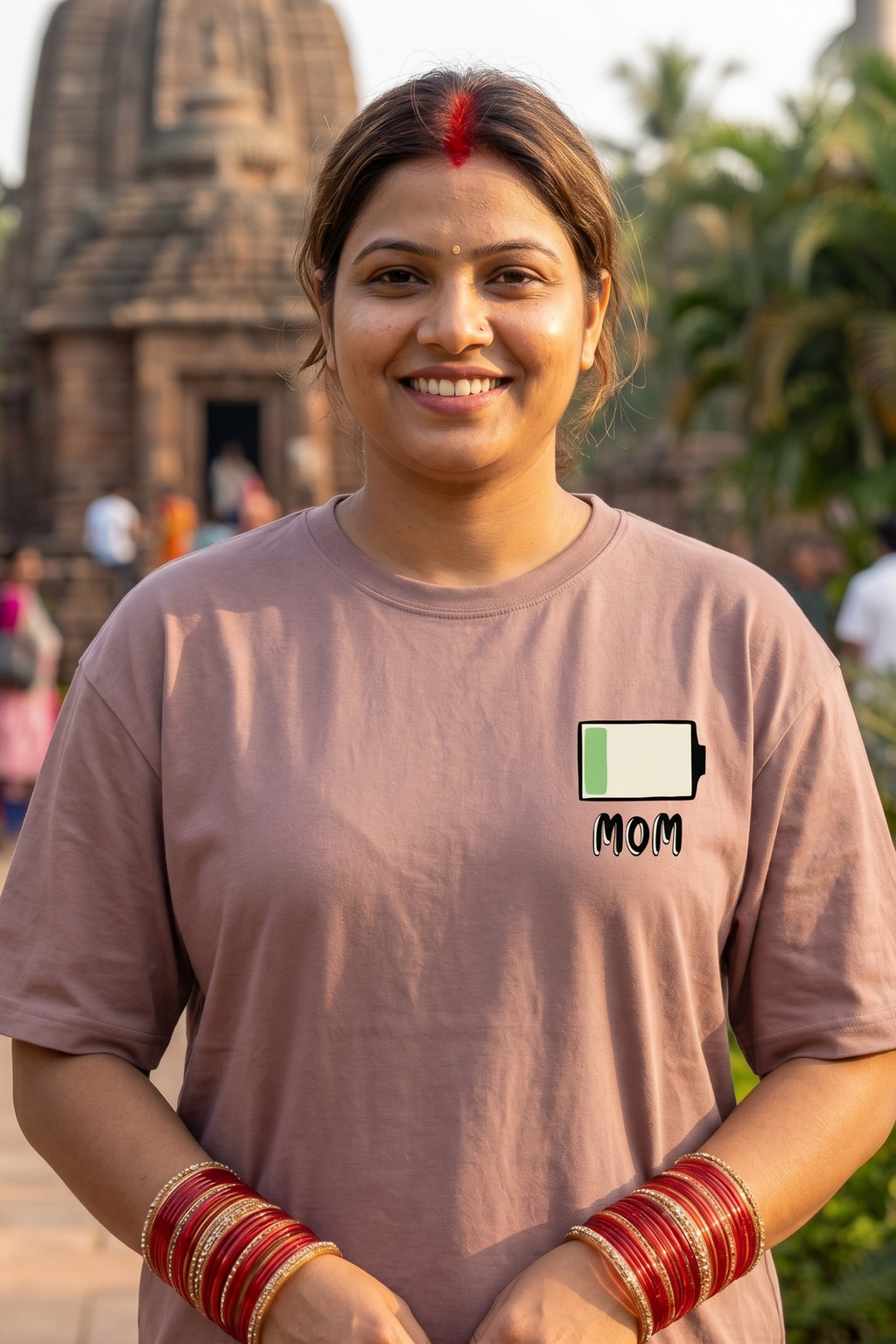 Woman wearing a t-shirt with a battery and 'MOM' graphic in front of a temple.