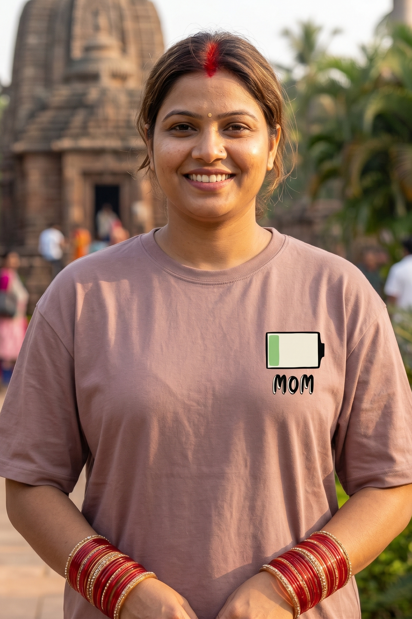 Woman wearing a t-shirt with a battery and 'MOM' graphic in front of a temple.