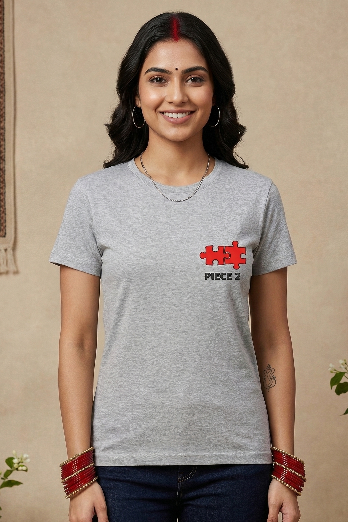 Woman wearing a gray t-shirt with a red and white logo indoors.